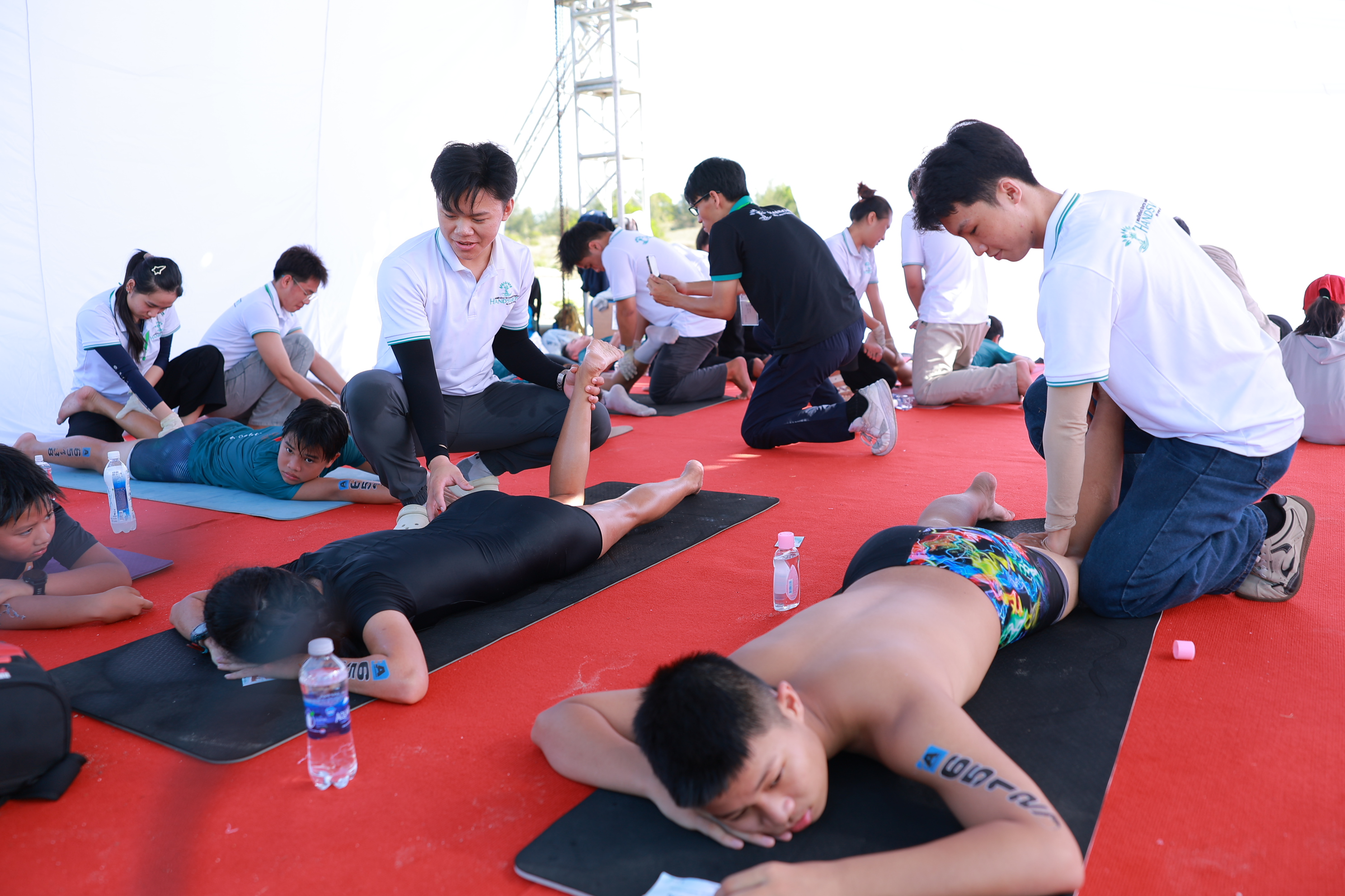 Hình ảnh KTV Hands Viet đang thực hiện các động tác giãn cơ, trị liệu chuyên sâu cho VĐV tại sự kiện